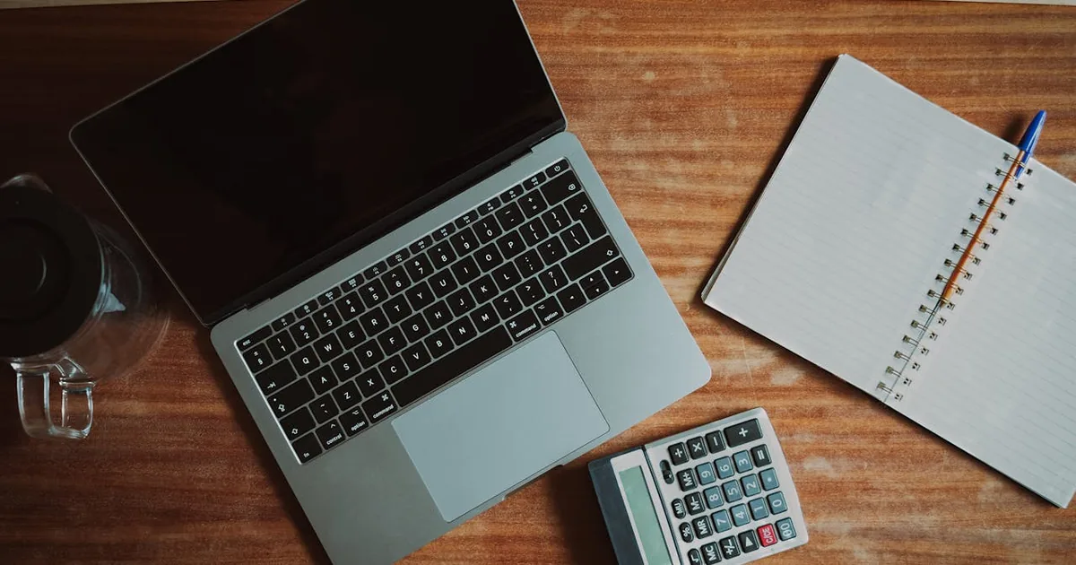 Accountant reviewing cross-border trade documents on laptop at desk — Shopify customs duty account in QuickBooks Online payout deposit