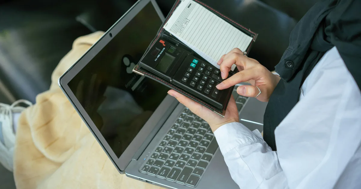 Person using a laptop and calculator — configuring QuickBooks Online Undeposited Funds for Shopify payout reconciliation